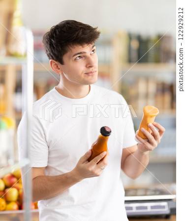Interested guy choosing natural sauce in grocery store 122929212