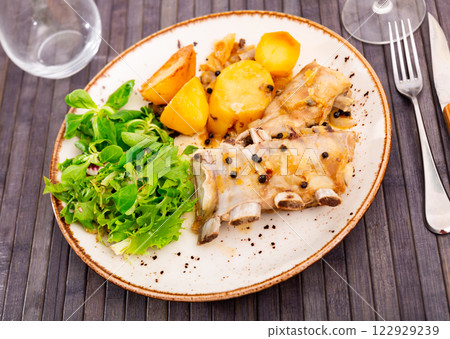 Appetizing grilled pork ribs with vegetable side dish of roasted potatoes garnished with greens and salad. Spanish cuisine Appetizing grilled pork ribs with vegetable side dish of roasted potatoes garnished with greens and salad. Spanish cuisine 122929239