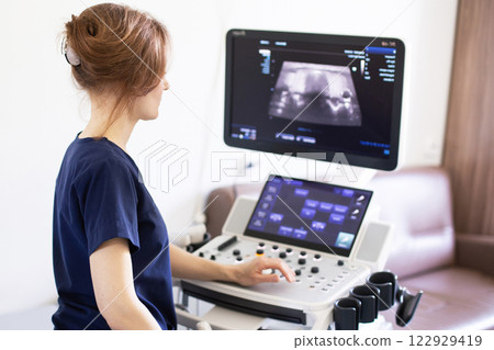 Doctor doing ultrasound scanning diagnostic of thyroid gland in clinic. 122929419