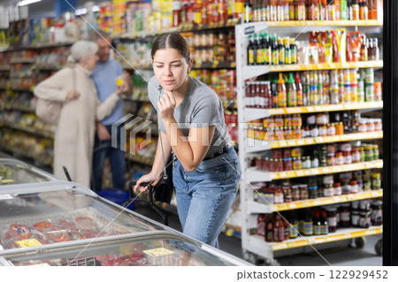 Young woman purchaser choosing frozen product in supermarket 122929452