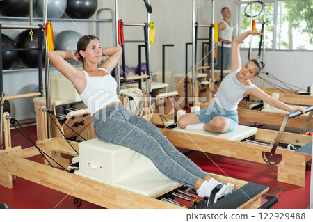 Young woman training her abs on pilates machine 122929488