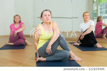 Active elderly woman practicing yoga at group 122929490