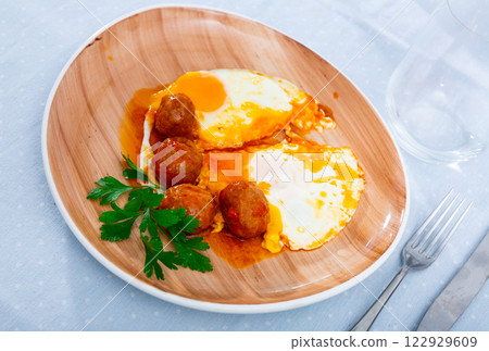 Plate of fried eggs and meatballs with sauce and greens Plate of fried eggs and meatballs with sauce and greens 122929609