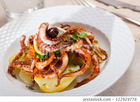 Seafood lunch. Tasty fried squid or octopus tentacles closeup 122929778