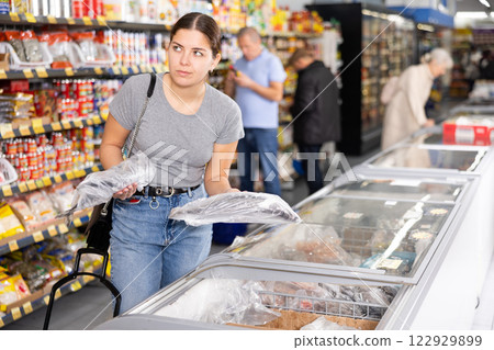 Young girl choosing frozen fish in freezer in grocery store 122929899