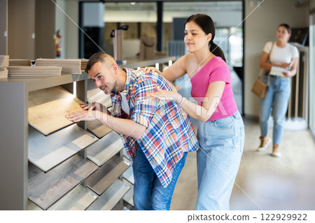 Girl and a friend choose laminate flooring in hardware store 122929922