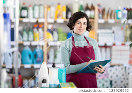 Middle-aged woman taking record of inventory in household store 122929962