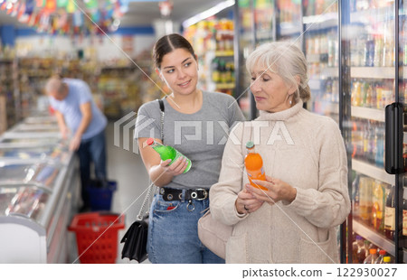 Woman purchasers choosing cool drink in big supermarket Woman purchasers choosing cool drink in big supermarket 122930027