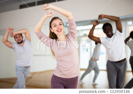 Young woman practicing vigorous dance movements with group Young woman practicing vigorous dance movements with group 122930186
