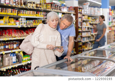 Man and woman purchasers choosing frozen product in supermarket 122930193