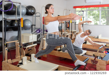 Young woman doing stretching on pilates reformer Young woman doing stretching on pilates reformer 122930269