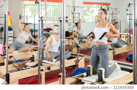 Young woman training her arms using straps 122930308