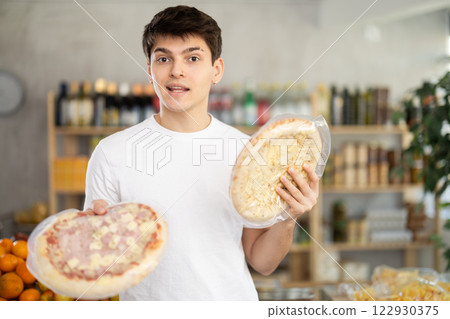 Male buyer carefully reads labels on frozen pizza - she chooses the best product in supermarket Male buyer carefully reads labels on frozen pizza - she chooses the best product in supermarket 122930375