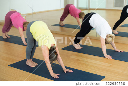 Fitness, sport and healthy lifestyle concept - mature woman doing yoga downward-facing dog pose on mat 122930538