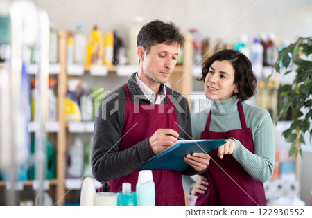 Two sellers makes notes on an paper - conducts an inventory in shop 122930552