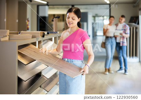 Young woman choosing laminate flooring in store 122930560