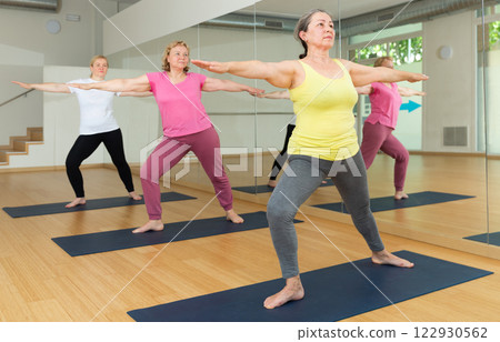 Women practicing yoga - virabhadrasana pose Women practicing yoga - virabhadrasana pose 122930562