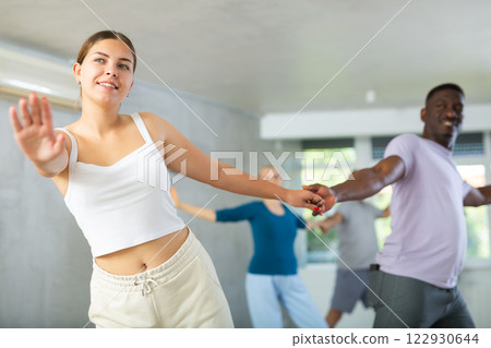 Girl teacher dances pair dance with african male student of fitness class 122930644