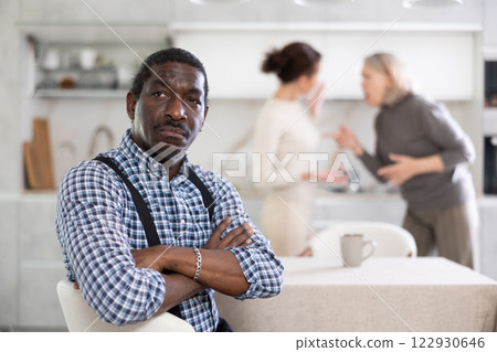 Adult sad man sitting at table during family quarrel Adult sad man sitting at table during family quarrel 122930646