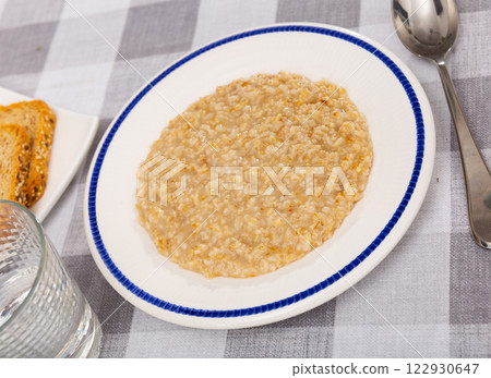 Boiled oatmeal porridge served in plate. Concept of diet food 122930647