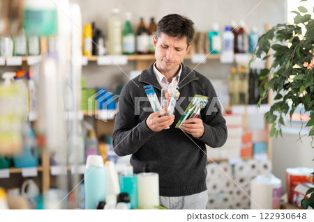 Among shop windows, man buyer leisurely examines goods and chooses toothbrush Among shop windows, man buyer leisurely examines goods and chooses toothbrush 122930648