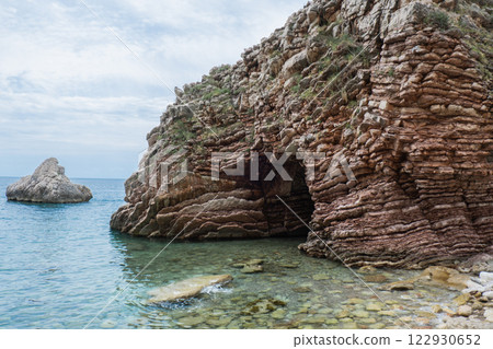 Beautiful rocks and bright turquoise water among layered rocks near Budva, Montenegro. Tropical summer landscape exotic beach on the Adriatic Sea. Vacation Beautiful rocks and bright turquoise water among layered rocks near Budva, Montenegro. Tropical summer landscape exotic beach on the Adriatic Sea. Vacation 122930652