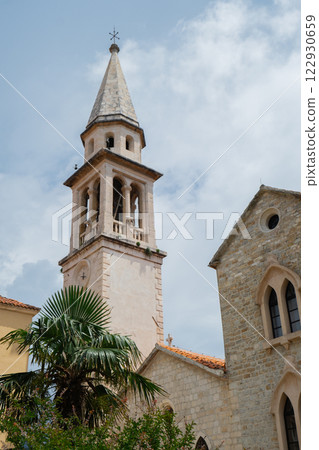 Budva, Montenegro picturesque old town and fortress walls architecture. Stunning showcasing historic stone buildings with red-tiled roofs traditional house. Spire of the chapel of The Church of Sveti 122930659