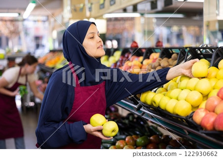 Young woman in hijab selling apples in grocery store Young woman in hijab selling apples in grocery store 122930662
