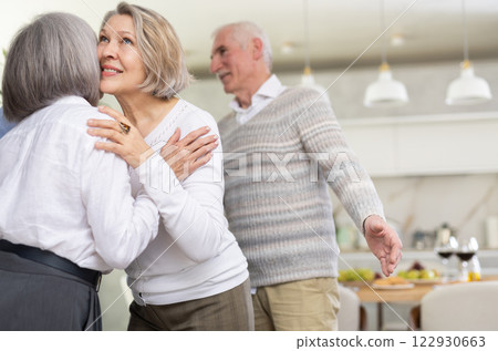 As two elderly woman meet, they exchange warm greeting by embracing with a gentle kiss on cheek As two elderly woman meet, they exchange warm greeting by embracing with a gentle kiss on cheek 122930663