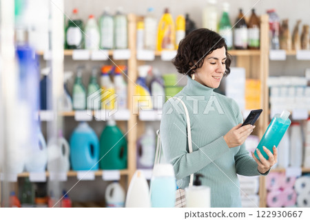 Middle-aged woman scanning QR-code on shampoo at department store 122930667