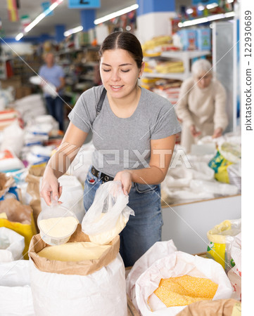 Young girl filling plastic bag with corn flour in supermarket 122930689