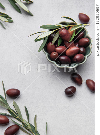 Kalamata olives with olive branch in green bowl on marble background Kalamata olives with olive branch in green bowl on marble background 122930697