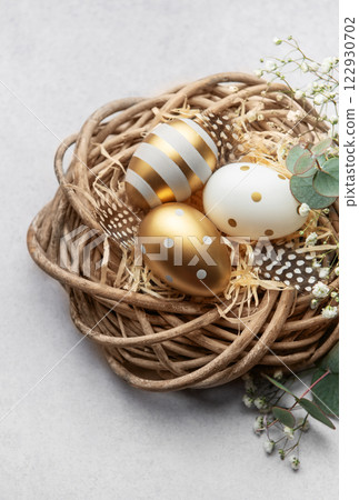Easter eggs resting in a decorative nest with feathers and gypsophila flowers 122930702