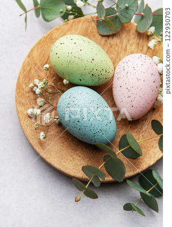 Pastel easter eggs on wooden plate with eucalyptus Pastel easter eggs on wooden plate with eucalyptus 122930703