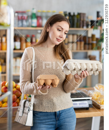 Young woman comparing egg cartons in grocery store 122930739