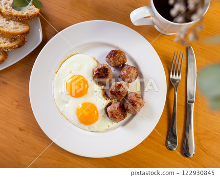 Fried eggs served with meatballs on plate 122930845