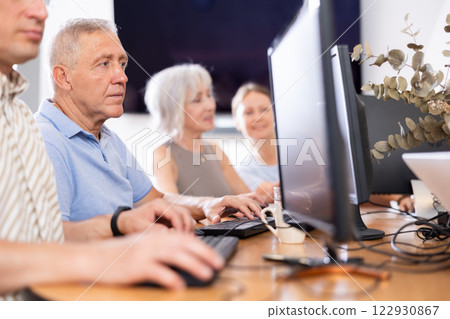 Concentrated elderly man immersed in using computer in library 122930867