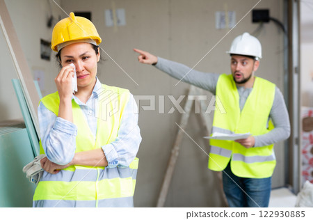 Woman engineer crying because she has been fired by her foreman Woman engineer crying because she has been fired by her foreman 122930885