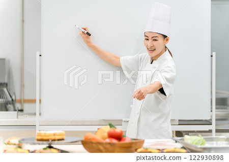 A female instructor who teaches at cooking seminars, vocational schools, and employee training 122930898