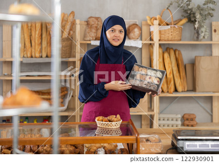 Asian Muslim woman bakery worker sells cookies in box, stand at counter and wait for visitors 122930901