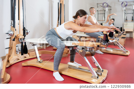 Young woman stretching her arms using pilates machine 122930986