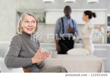 Elderly woman smiling during family quarrel Elderly woman smiling during family quarrel 122931020
