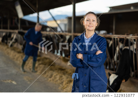 Portrait of female farm owner in cowshed Portrait of female farm owner in cowshed 122931077