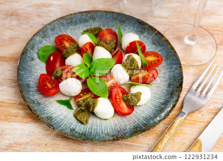 Caprese with basil leaves and pesto sauce on table Caprese with basil leaves and pesto sauce on table 122931234