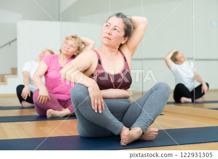 Active senior woman practicing yoga at group Active senior woman practicing yoga at group 122931305