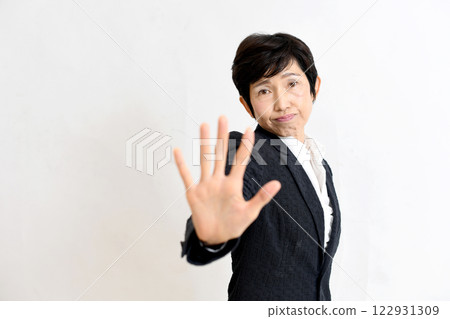 A middle-aged woman in a suit sticking out her hand to warn others A middle-aged woman in a suit sticking out her hand to warn others 122931309