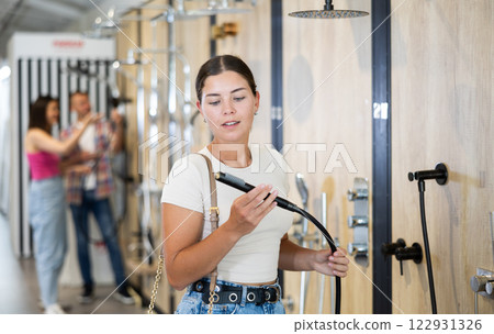 Female buyer choosing shower head in hardware store Female buyer choosing shower head in hardware store 122931326