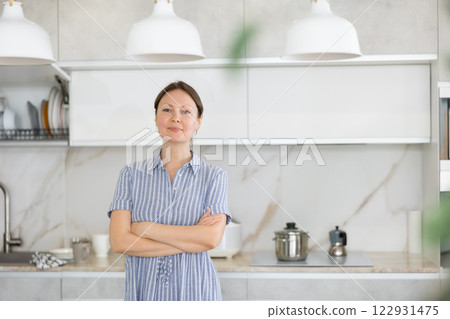 Young housewife is standing in modern home kitchen. 122931475