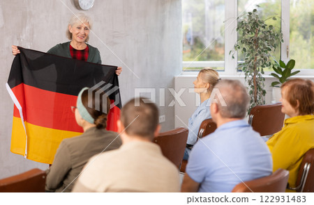 Mature female professor showing german flag to elderly students 122931483