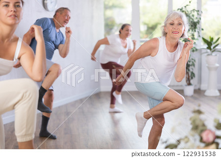 Group of happy mature sports women and man in activewear exercising dynamic dancing movemens in gym studio Group of happy mature sports women and man in activewear exercising dynamic dancing movemens in gym studio 122931538